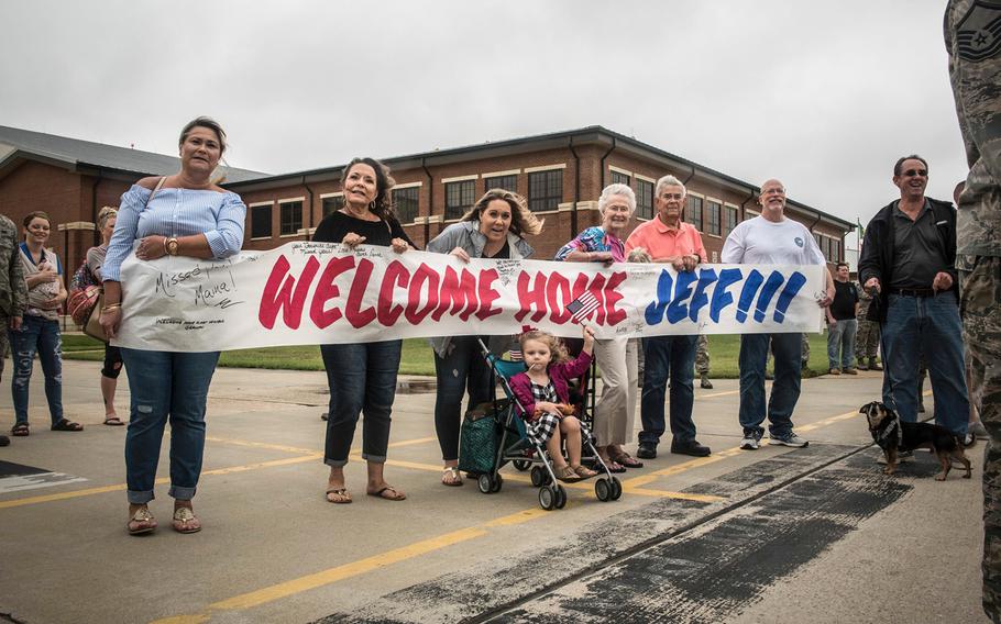 Family members of Virginia Air National Guard Staff Sgt. Jeff Greenquist, hold a welcome-home sign, celebrating his return from the Middle East at Joint Base Langley- Eustis, Va., on Thursday, Oct. 12, 2017.