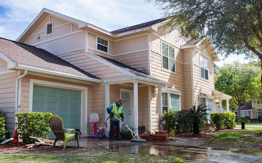 A maintenance worker for Balfour Beatty Housing washes the driveway of a home at Marsh Cove, a military residential community at Naval Station Mayport, Fla..
