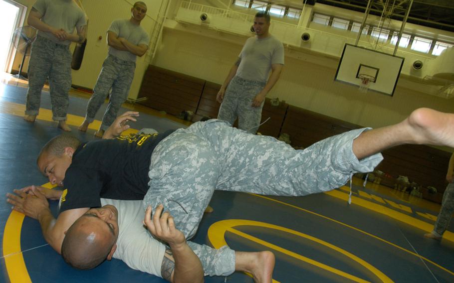 Combatives instructor Army Sgt. Matthew Prout, 26, of Baltimore, Ma. (blue shirt) demonstrates the correct way to knee an opponent in the ribs with the help of Air Force Tech Sgt. Jordan Acosta, 29, of Wahiawa, Hawaii at Yokota Air Base last Friday.