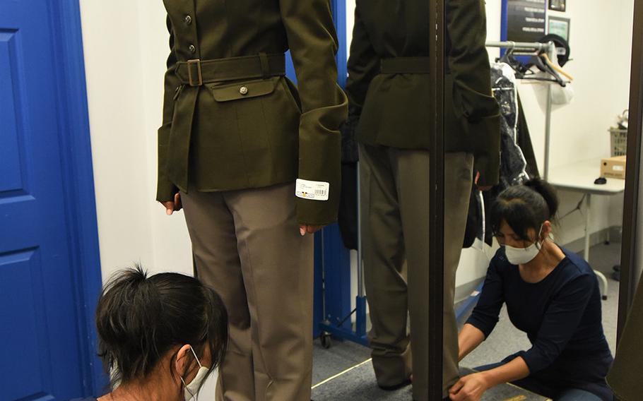 A female soldier attending the Army Recruiter Course at Fort Knox, Ky., has her pants hem measured by a seamstress after receiving the Army Green Service Uniform, July 8, 2020. 