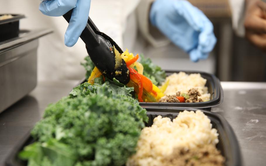 Pfc. Erica Kenmegne, a culinary specialist with 10th Mountain Division, adds the final touch to a Meal Prep to-go meal at the Commando Warrior Restaurant at Fort Drum, N.Y.,  Jan.11, 2021. 
