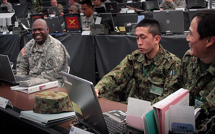 A U.S. soldier chats with his counterparts from Japan's Western Army during the first day of the bilateral Yama Sakura exercise.  The drill tests the ability of U.S. and Japanese ground forces to coordinate communications, intelligence-sharing and troop movements in a computer-simulated environment at Camp Kengun in southwestern Japan.