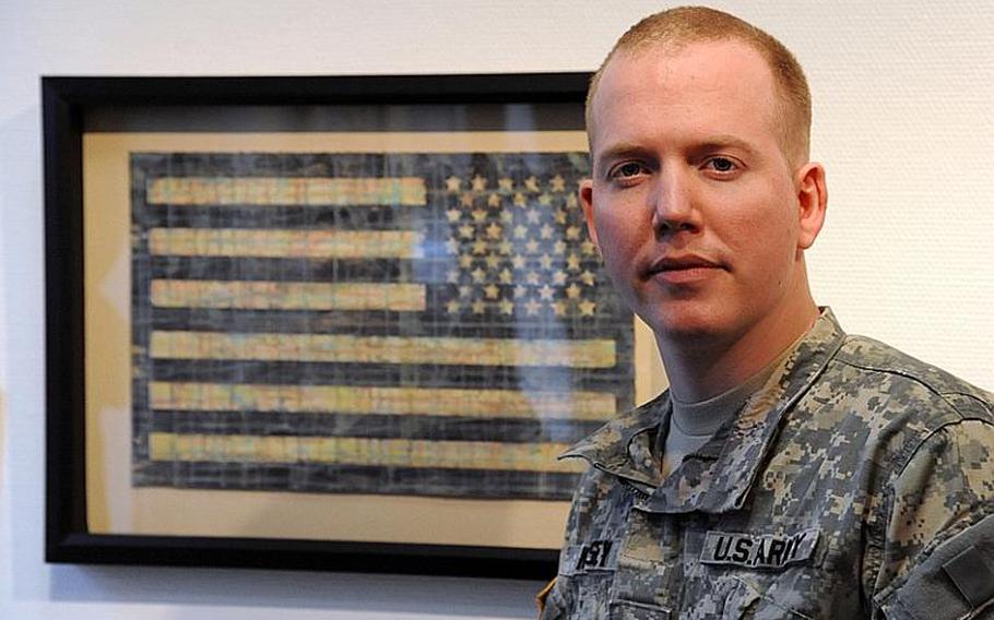 Sgt. Ron Kelsey stands in front of his piece 'Homecoming IR Flag,' a work of art he originally commissioned to be given to soldiers returning from Iraq. Kelsey, 30, currently serves as the scheduler for the command sergeant major of U.S. Army Europe in Heidelberg, Germany.