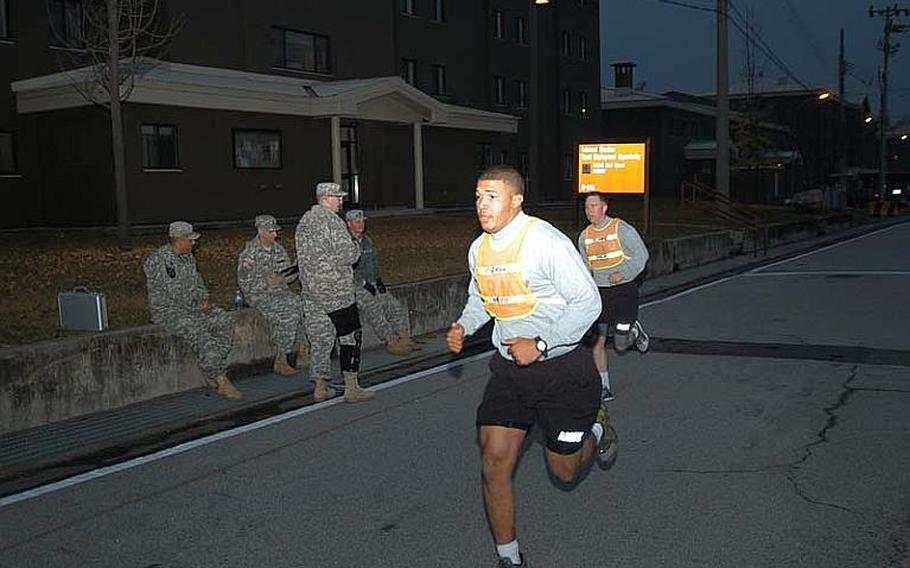 Spc. Devin Sanders, back, takes part in the two-mile run portion of his unit physical fitness test Nov. 7, 2012, at Camp Red Cloud in South Korea in advance of his planned attendance at Warrior Leader Course. Sgt. Adan Altagracia, front, sets the pace for Sanders in trying to help him maximize his fitness score. The Army this month reinstituted physical fitness standards required for participation in professional military education courses.