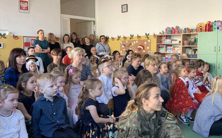 A Romanian soldier, right, and guests watch a singing competition at the Miejskie Przedszkole school in Elk, Poland, Feb. 5, 2020.
