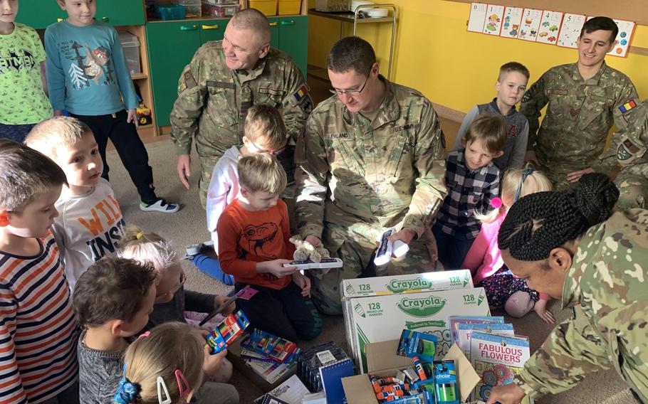 U.S. Army Sgt. Austin Eveland, center, hands out school supplies to children at the Miejskie Przedszkole schooll in Elk, Poland, Feb. 5, 2020.