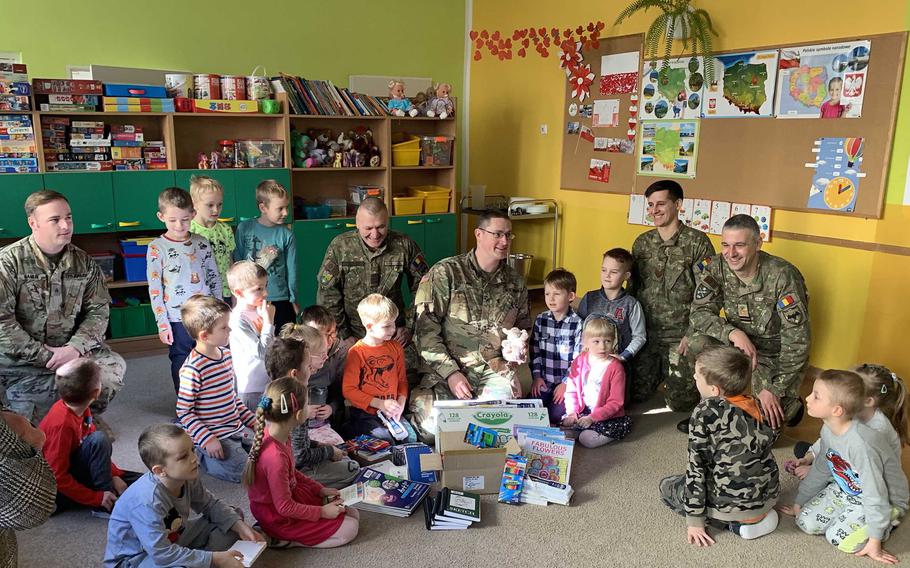 U.S. and Romanian soldiers talk with children after giving out school supplies at the Miejskie Przedszkole school in Elk, Poland, Feb. 5, 2020.