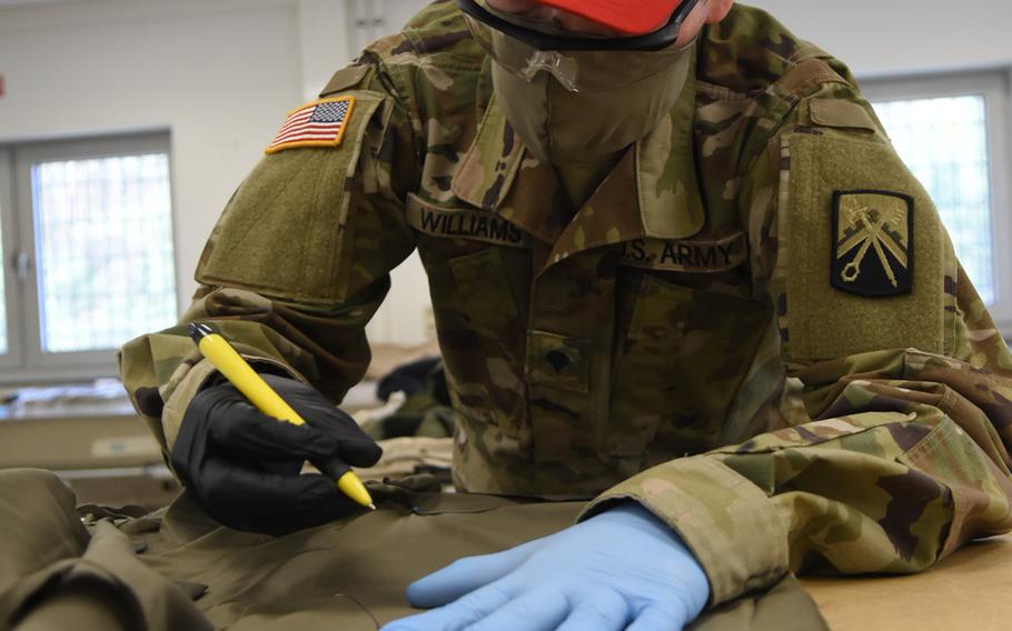 Spc. Freddy Williams, a parachute rigger with the 5th Quartermaster-Theater Aerial Delivery Company at Rhine Ordnance Barracks, Germany, cuts fabric from a bedsheet that will be sewn into a face mask for soldiers in Europe, including the 21st Theater Sustainment Command.