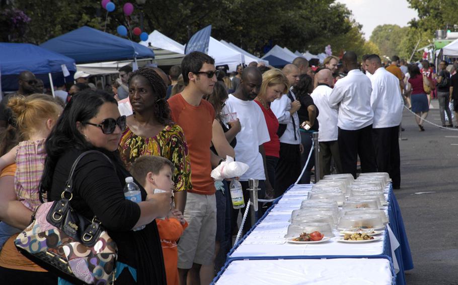 Crowds of people pass by culinary works of military chefs competing in a cooking competition at a fall festival outside the Marine Barracks in Washington, D.C., on Saturday, Sept. 22, 2012.