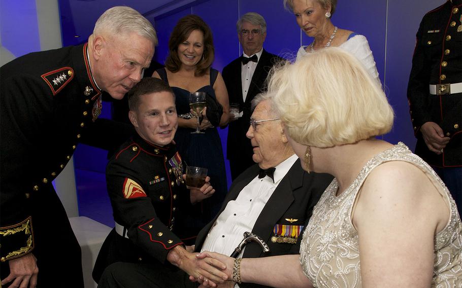 Marine Cpl. William Kyle Carpenter kneels beside Gen. James F. Amos, the 35th Commandant of the Marine Corps, while being introduced to guests at the Gaylord National Resort and Convention Center, at the National Harbor in Maryland on Nov. 9, 2013.