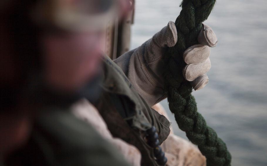 A Marine with Company C, 3rd Platoon, of the Fleet Anti-Terrorism Security Team grabs the rope as he prepares to fast-rope out an MH-60 Seahawk during training aboard the afloat forward staging base USS Ponce, Sept. 18, 2015.  
