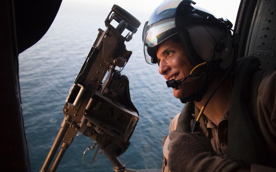 Naval air crewman 3rd Class Robert Marsh, aboard an MH-60 Seahawk, sits in the gunners position during fast-rope training for the Marines with Company C, 3rd Platoon, of the Fleet Anti-Terrorism Security Team, aboard the afloat forward staging base USS Ponce, Sept. 18, 2015.  FAST trains to provide quick-reaction reinforcement of security at U.S. naval and national assets, including U.S. embassies, for a limited duration.