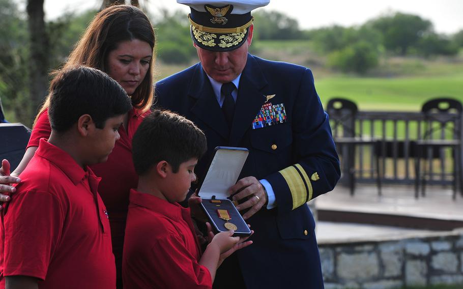 Rear Adm. Dave Callahan, 8th Coast Guard District commander, presents the Gold Lifesaving Medal to the family of retired Marine Corps Master Sgt. Rodney Buentello July 31, 2017, in San Antonio. 