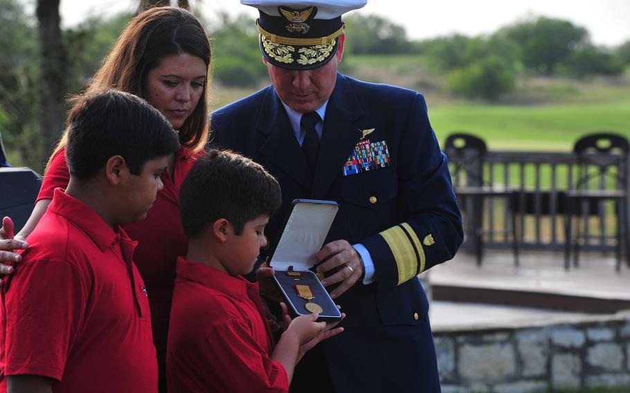 Rear Adm. Dave Callahan, 8th Coast Guard District commander, presents the Gold Lifesaving Medal to the family of retired Marine Corps Master Sgt. Rodney Buentello July 31, 2017, in San Antonio.