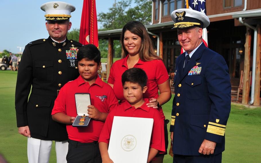 U.S. Marine Corps Lt. Col. Jeff Buffa, 4th Reconnaissance Battallion, and Rear Adm. Dave Callahan, 8th Coast Guard District commander, take a moment for a photo with the family of retired Marine Corps Master Sgt. Rodney Buentello after a ceremony to posthumously award the Gold Lifesaving Medal on July 31, 2017, in San Antonio. 