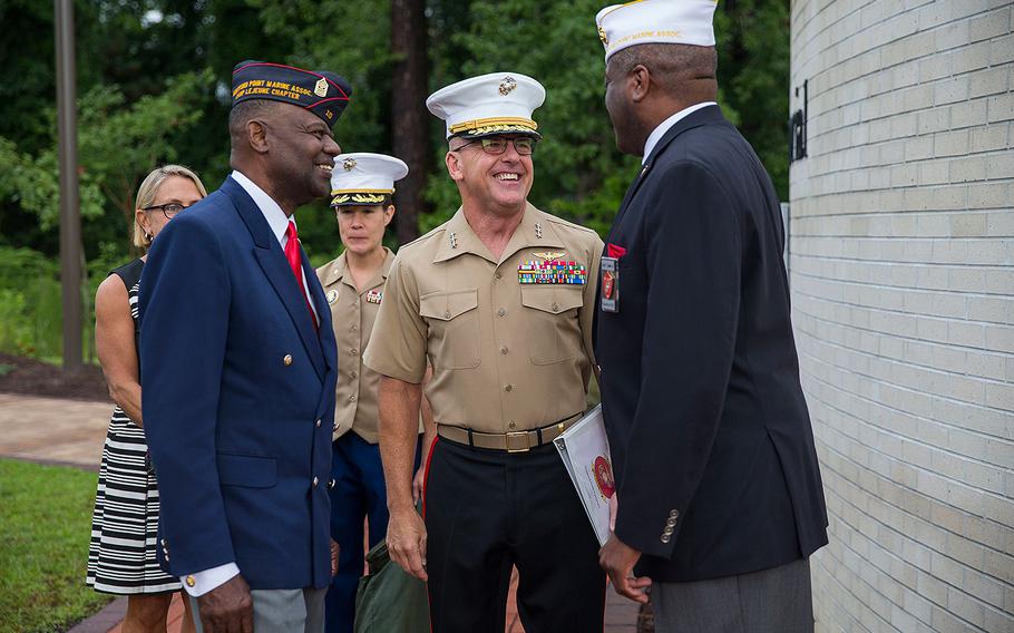 Lt. Gen. Robert F. Hedelund, commanding general, II Marine Expeditionary Force, center, is greeted by Forest Spencer, right, national president, Montford Point Marine Association, during the Montford Point Marine Memorial gifting ceremony at the Montford Point Marine Memorial in Jacksonville, N.C., July 25, 2018. 