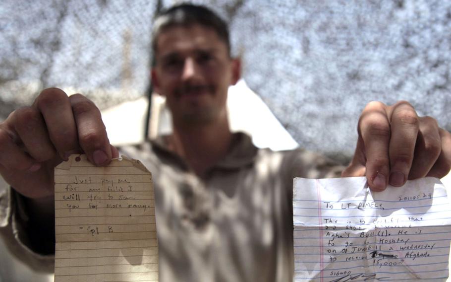 First Lt. Chad Pimley, a 24-year-old forward observer pulling double duty as a civil affairs officer, displays two notes written by Marines and given to Afghans who were requesting compensation for damages.