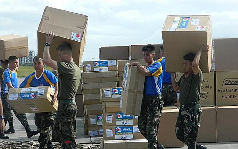 Philippine servicemembers and U.S. Marines handle relief supplies Dec. 13, 2012, at Villamor Air Base in Manila during humanitarian assistance and disaster relief operations.