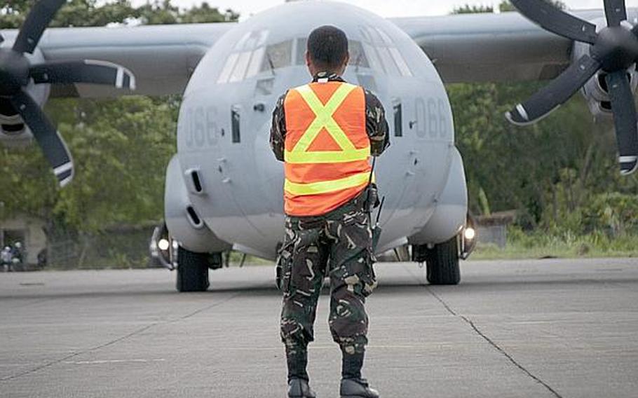A member of the Philippine army marshals a KC-130J aircraft Dec. 14, 2012, on the tarmac at Davao International Airport. The aircraft arrived carrying supplies for citizens who were displaced following Typhoon Bopha this month. The KC-130 flights were flown daily from Manila to the Mindanao region.