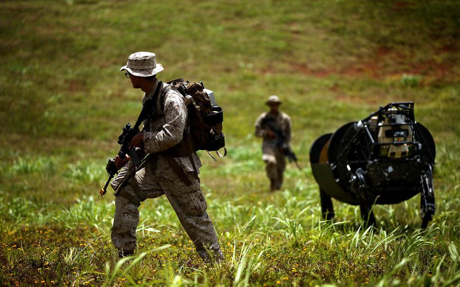 Lance Cpl. Brandon Dieckmann and Pfc. Huberth Duarte, of the 3rd Battalion, 3rd Marine Regiment, walk with the Legged Squad Support System, known as BigDog, during a 2014 exercise in Hawaii. The Marine Corps recently shelved plans to field the robot, a 240-pound machine capable of carrying 400 pounds of supplies for troops on patrol.