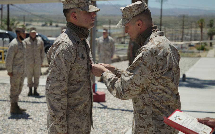 U.S. Marine Corps Maj. Gen. Robert Castellvi, right, presents the Navy and Marine Corps Commendation Medal to Cpl. Andrew C. Tate at Marine Corps Air Ground Combat Center, Twentynine Palms, Calif., May 4, 2020. Tate was awarded the medal for rescuing a motorist from an overturned car in May 2019.