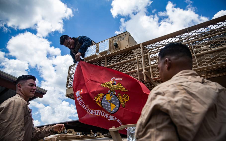 U.S. Marine Corps 1st Lt. Seth Gillen, Cpl. Jonathan Villanueva and Staff Sgt. Stephen Leon Guerrero, from left, with 2nd Tank Battalion, 2nd Marine Division hang a Marine Corps flag on the rear of an M1A1 Abrams tank on Camp Lejeune, N.C., July 27, 2020.