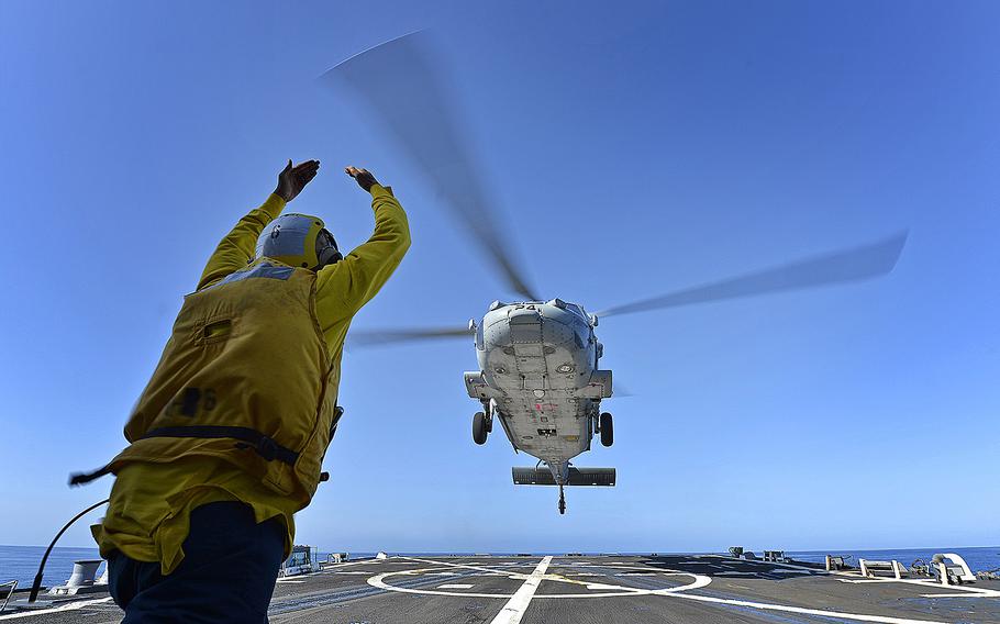 A sailor aboard the USS Pinckney gives hand signals during deck landing qualification training while at sea on April 25, 2013. The Navy on Saturday, March 8, 2014, dispatched the Arleigh Burke-class guided-missile destroyer to aid in the search of a Malaysian airliner in the South China Sea.