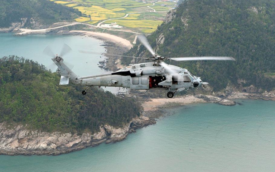 An MH-60S Sea Hawk helicopter conducts search-and-rescue operations from the amphibious assault ship USS Bonhomme Richard on Tuesday, April 22, 2014, near the site of the sunken South Korean ferry Sewol in the East China Sea.