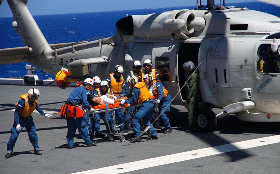 Sailors on the Japanese destroyer Ise transfer an injured man to a gurney Saturday, July 13, 2014, as part of a mock typhoon disaster drill during the 2014 Rim of the Pacific exercise in Hawaii. The Ise crew practiced procedures for receiving and treating victims of natural disasters.