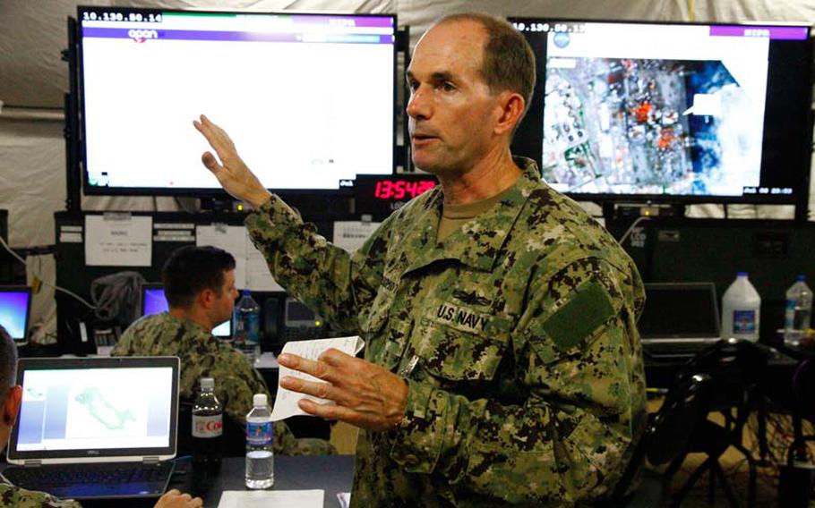 Commodore Chris Peterschmidt explains the workings of the communication system used in the humanitarian/disaster assistance drill Saturday, July 12, 2014, that's part of the month-long Rim of the Pacific exercise. The headquarters is located side-by-side with Japan's on Ford Island in Pearl Harbor.