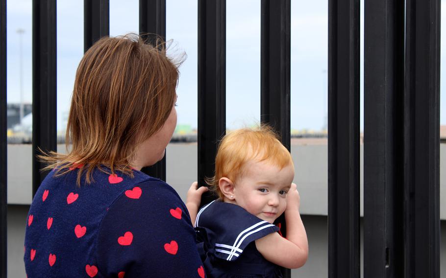 Shawna Tooman and 21-month-old Brooke look through a gate as the USS Sampson leaves Naval Base San Diego on Friday, Oct. 31, 2014, for a deployment to the western Pacific. Brooke's father, Petty Officer 3rd Class Taylor Tooman, is a member of the ship's crew.