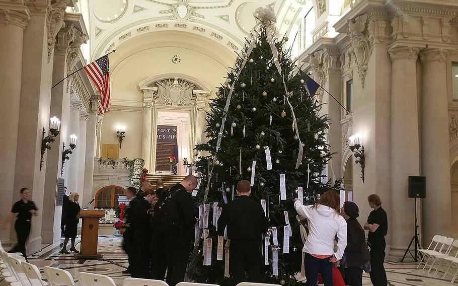Personnel at the U.S. Naval Academy in Annapolis, Md., surround a Giving Tree decorated with paper angel ornaments each of which contain the wish list of a local child. Participants in the annual holiday event will then purchase a gifts for the children listed on the ornaments.