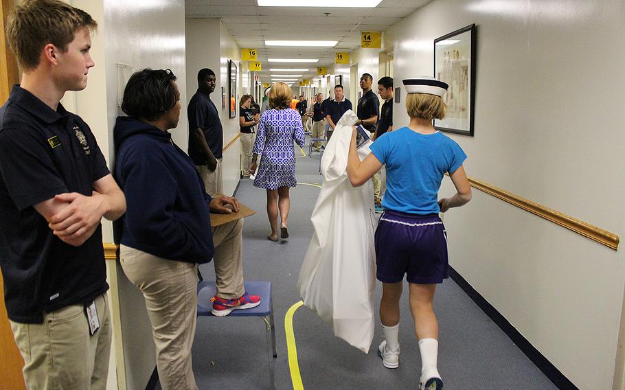 An incoming Naval Academy plebe leaves one station and heads to the next to retrieve her uniform during Induction Day on Thursday, June 30, 2016.