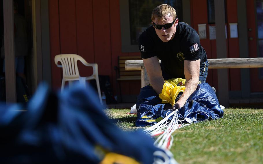 Petty Officer 1st Class Remington Peters, a member of the U.S. Parachute Team, the Leap Frogs, packs his parachute after a practice demonstration in Eloy, Arizona on Feb. 9, 2016.