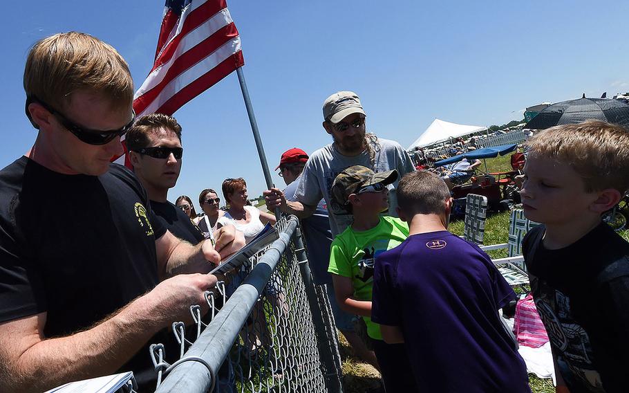 Petty Officer 1st Class Remington Peters, a member of the U.S. Navy Parachute Team, the Leap Frogs, signs an autograph for a young fan after a demonstration at the Dayton Air Show on June 19, 2016.