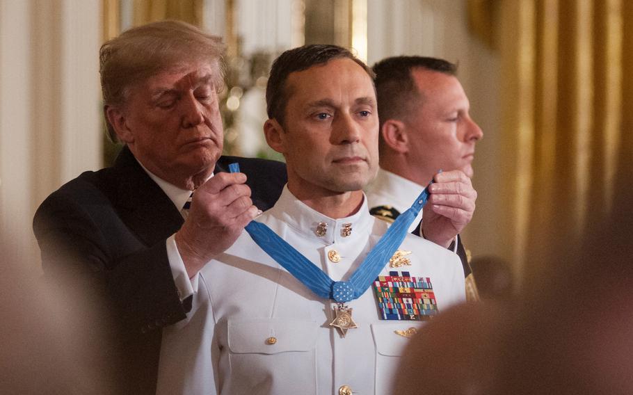 President Donald Trump presents the Medal of Honor to retired Navy SEAL Master Chief Petty Officer Britt Slabinski who was recognized for his bravery and heroic actions in what is known as the Battle of Roberts Ridge in Afghanistan in March 2002.