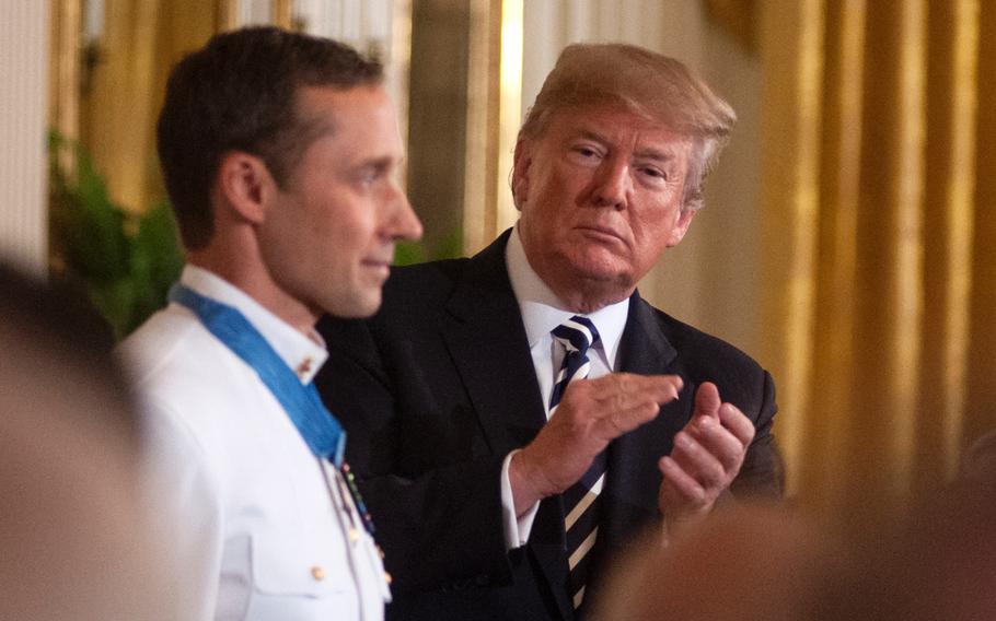 President Donald Trump applauds retired Navy SEAL Master Chief Petty Officer Britt Slabinski who was presented the Medal of Honor at the White House in Washington, D.C., on Thursday, May 24, 2018, during a ceremony in which Slabinski was recognized for his bravery and heroic actions in what is known as the Battle of Roberts Ridge in Afghanistan in March 2002.