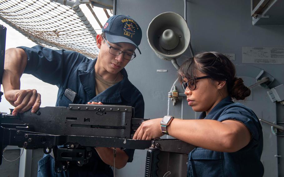 Gunner's Mate Seaman Jose Garciaflores and Gunner's Mate 3rd Class Anne Canta work on a .50-caliber machine gun aboard the USS America in the Philippine Sea on April 8, 2020.