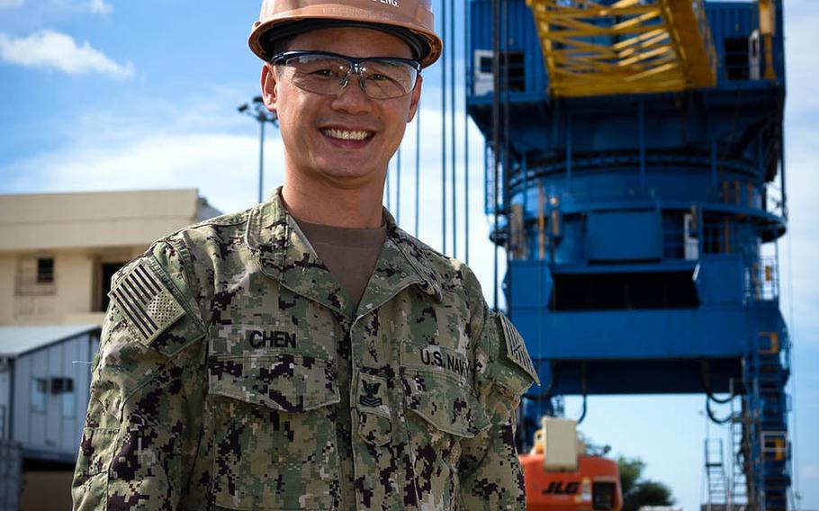 Michael Chen, an electrician's mate first class, poses in front of one of the massive cranes at the Pearl Harbor Naval Shipyard and Intermediate Maintenance Facility in Hawaii.
