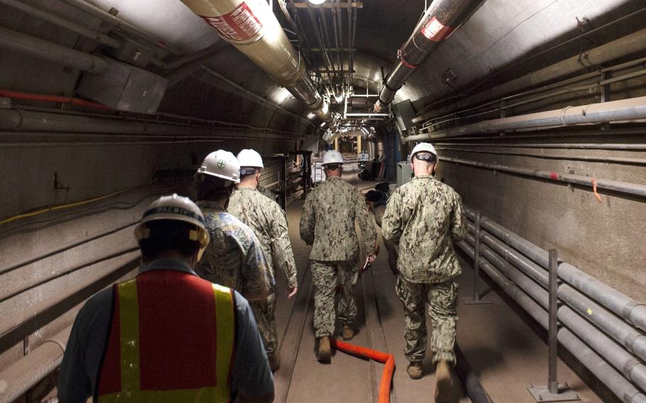 Several men walk through a tunnel.