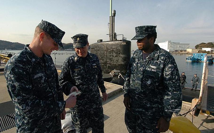 Chief Petty Officer Mark Wachter, center, hands out nicotine gum to Petty Officer 1st Class John Steimel, left, and Seaman Shaquan Topping during a USS Charlotte port visit Thursday at Yokosuka Naval Base, Japan. 
