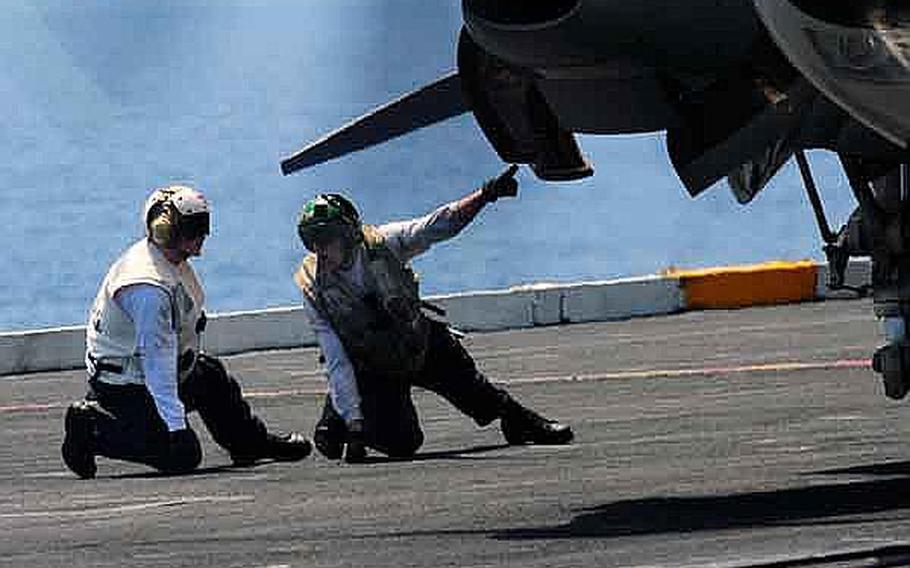An aviation machinist&#39;s mate, right, walks a hospital corpsman through a pre-flight inspection of an E-2C Hawkeye aboard the aircraft carrier USS Ronald Reagan. The Ronald Reagan Carrier Strike Group is operating in the western Pacific Ocean. The Navy announced Thursday that it would be cutting 3,000 sailors in the ranks of E-4 to E-8 from overmanned career fields, such as the  aviation machinist&#39;s mate rating.