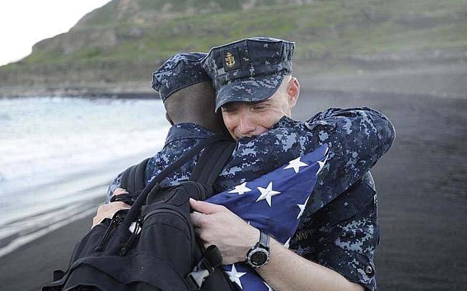 Chief Petty Officer Andrew Thomasson, right, hugs Senior Chief Ken Ballard after he laid his grandfather's ashes to rest at Iwo Jima's Invasion Beach. More than 60 Navy Misawa chief petty officers and chief petty officer selectees took part in a remembrance ceremony for Thomasson's grandfather, Oscar Thomasson, who took part in the initial assault during the Battle for Iwo Jima. Andrew Thomasson plans to take the flag shown here home to present it to Oscar's widow, Betty, who now lives in Kansas.