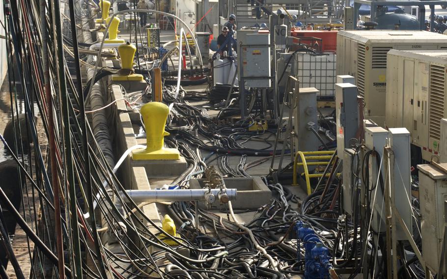 A mass of cables and hoses on the pier provide power and water to the USS Essex as the ship begins an 18-month maintenance period.