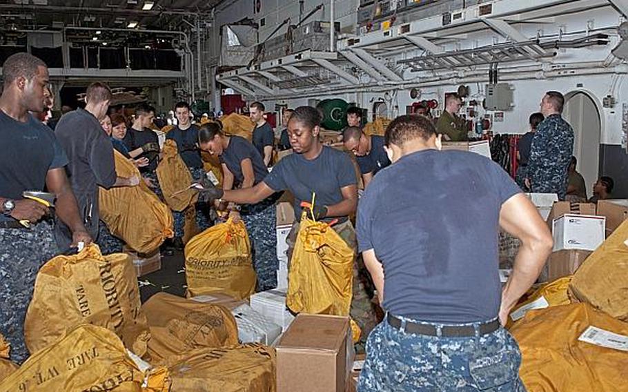 Sailors sort mail in the hangar bay of the amphibious assault ship USS Peleliu (LHA 5) during a replenishment at sea March 17 in the U.S. 5th Fleet area of responsibility.