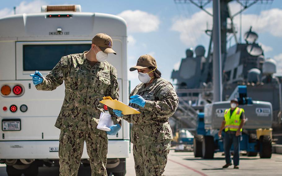 Sailors check muster sheets May 18, 2020, during a crew swap for the USS Kidd, docked in San Diego, in the next phase of the Navy's plan to eradicate the coronavirus from the ship and crew.