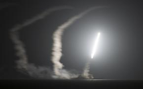 A missile flies in the air over water at night.