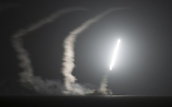 A missile flies in the air over water at night.