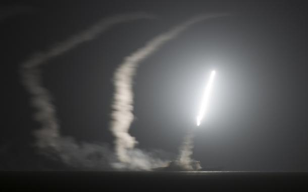 A missile flies in the air over water at night.