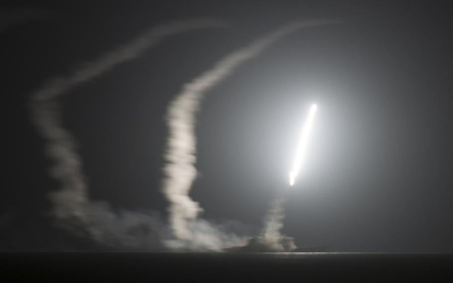 A missile flies in the air over water at night.